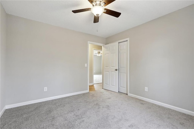 unfurnished bedroom with a closet, carpet flooring, ceiling fan, and baseboards