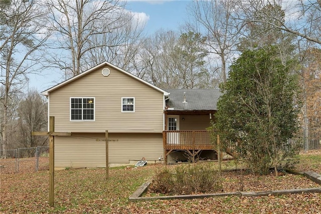 rear view of house featuring fence and a wooden deck