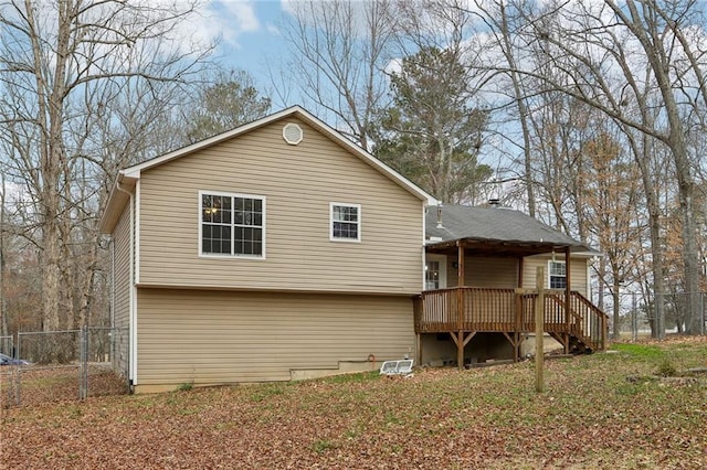 rear view of house featuring fence and a wooden deck