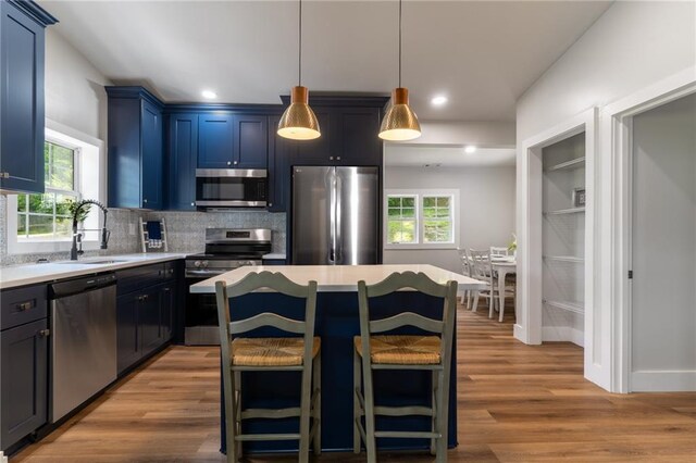 235 Lowry St, Ball Ground, GA 30107 - kitchen with appliances with stainless steel finishes, a sink, blue cabinets, light wood-style flooring, and decorative backsplash