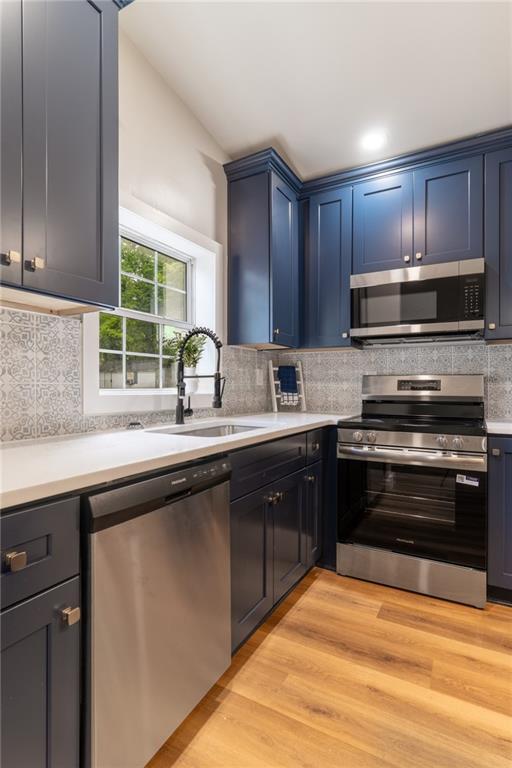 235 Lowry St, Ball Ground, GA 30107 - kitchen featuring appliances with stainless steel finishes, a sink, light countertops, backsplash, and light wood-type flooring