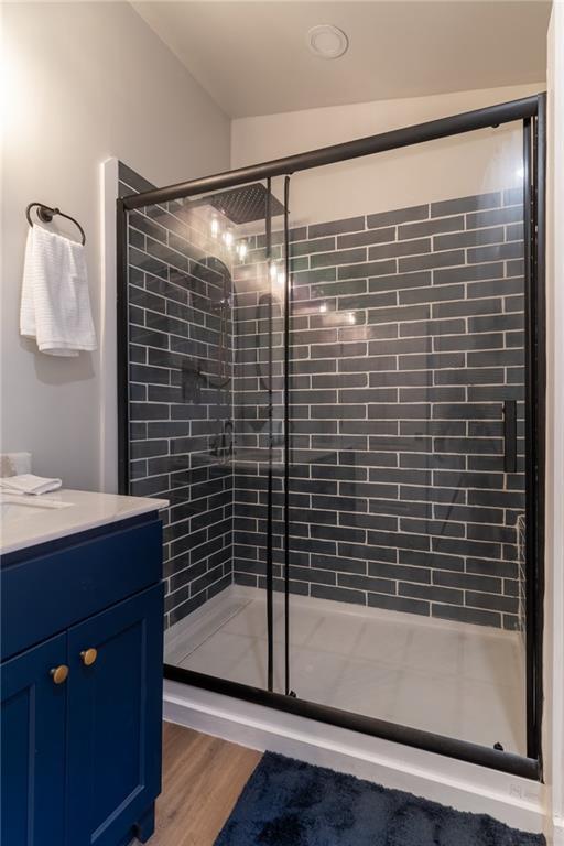 235 Lowry St, Ball Ground, GA 30107 - bathroom featuring a stall shower, vanity, and wood finished floors
