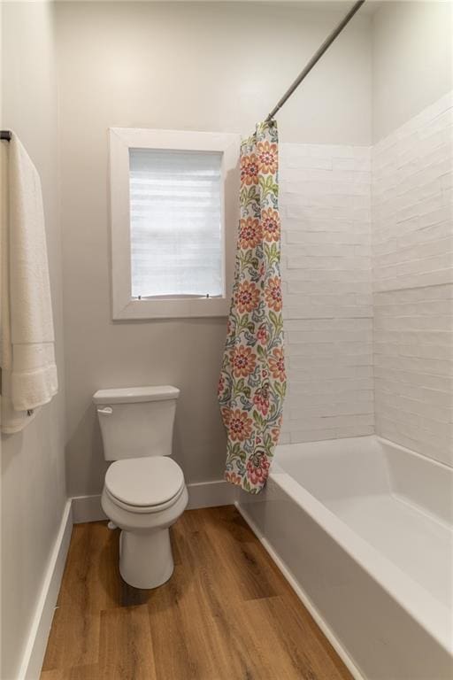 235 Lowry St, Ball Ground, GA 30107 - bathroom featuring wood finished floors, toilet, baseboards, and shower / tub combo with curtain