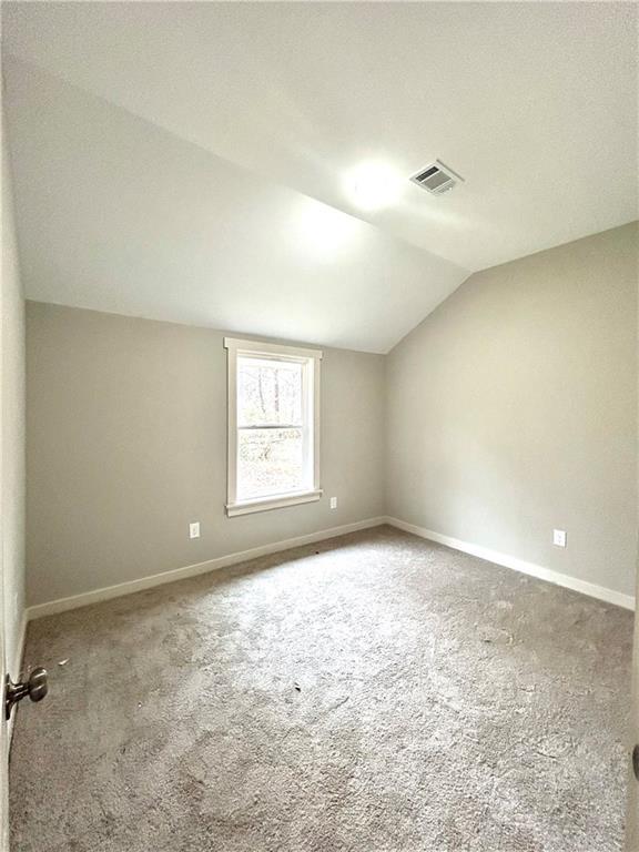 10033 Florence Cir, Villa Rica, GA 30180 - spare room featuring vaulted ceiling and carpet flooring