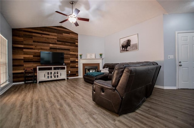 living room with hardwood / wood-style flooring, ceiling fan, vaulted ceiling, and wood walls