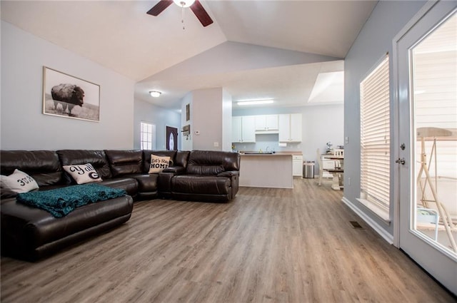 living room with lofted ceiling, ceiling fan, and light wood-type flooring