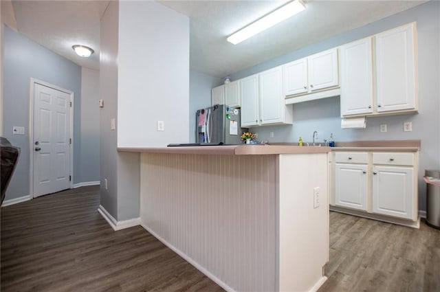 kitchen featuring hardwood / wood-style flooring, white cabinetry, a kitchen breakfast bar, stainless steel fridge with ice dispenser, and kitchen peninsula