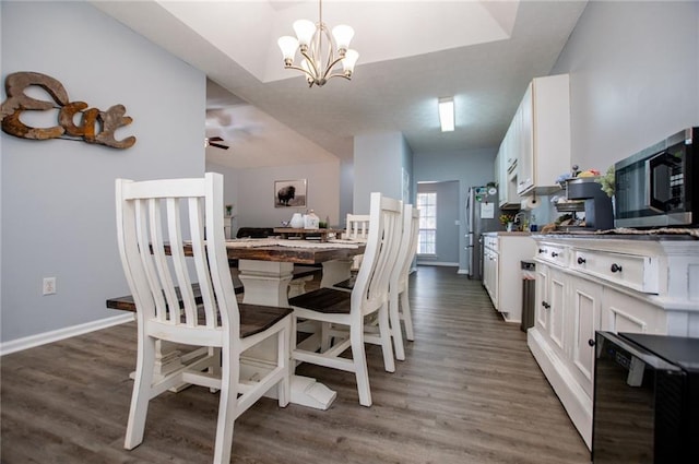 dining area featuring dark wood-type flooring, ceiling fan with notable chandelier, and beverage cooler