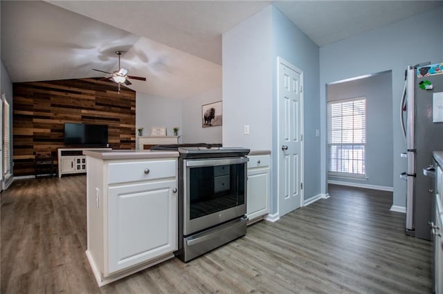 kitchen with white cabinetry, wooden walls, stainless steel appliances, and light hardwood / wood-style flooring