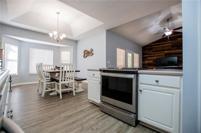 kitchen featuring decorative light fixtures, wooden walls, white cabinets, and stainless steel electric range oven