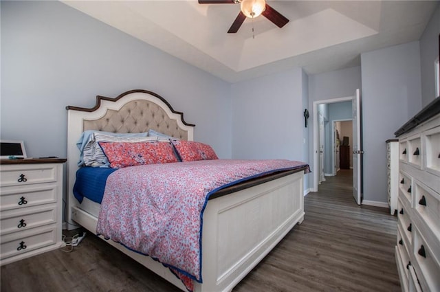 bedroom featuring dark wood-type flooring, ceiling fan, and a raised ceiling