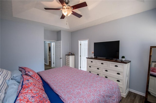 bedroom featuring dark wood-type flooring, ceiling fan, and a tray ceiling