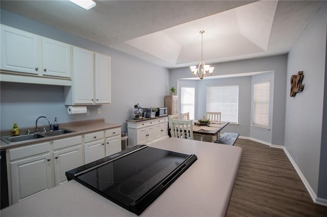 kitchen with a tray ceiling, sink, hanging light fixtures, and white cabinets