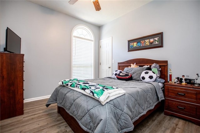 bedroom featuring ceiling fan, dark hardwood / wood-style floors, and multiple windows