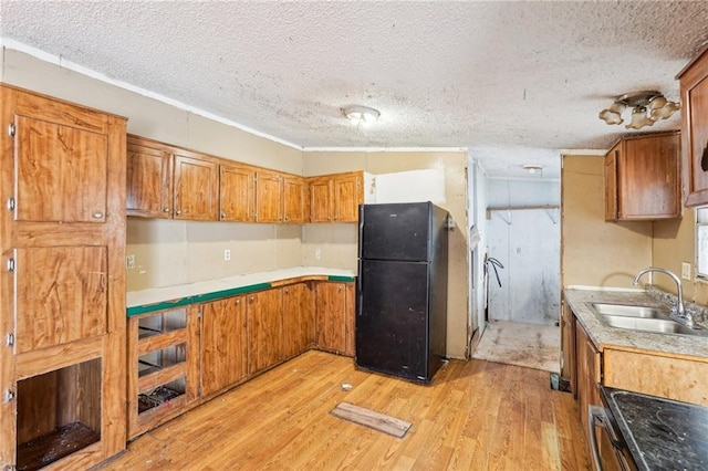 kitchen featuring black refrigerator, sink, light hardwood / wood-style flooring, and a textured ceiling