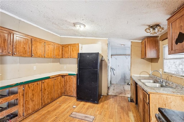 kitchen featuring sink, black fridge, a textured ceiling, light wood-type flooring, and stove