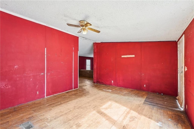 spare room featuring ceiling fan, wood-type flooring, vaulted ceiling, and a textured ceiling