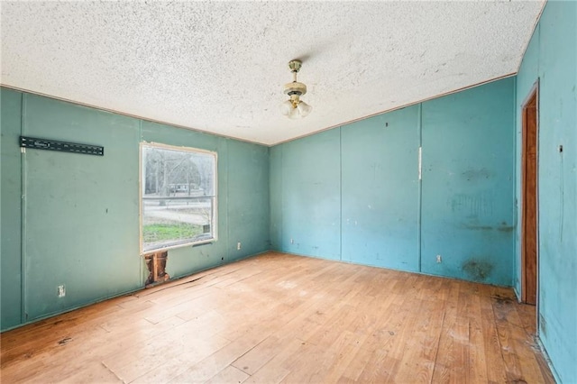 spare room with a textured ceiling and light wood-type flooring