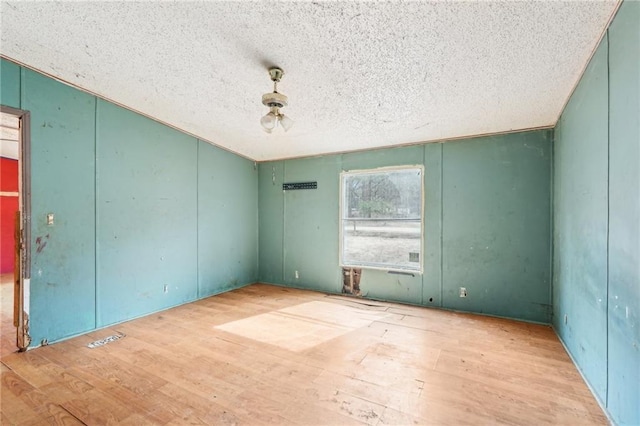 unfurnished room featuring a textured ceiling and light wood-type flooring