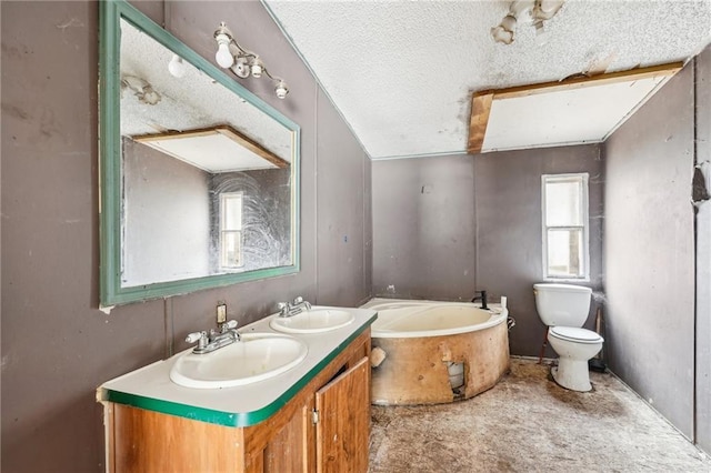 bathroom featuring vanity, a washtub, a textured ceiling, and toilet