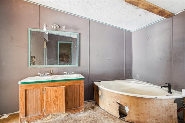 bathroom with vanity, a bath, and a textured ceiling