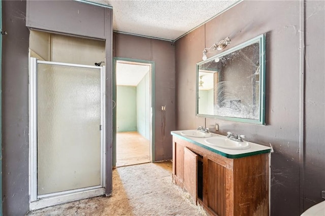 bathroom featuring walk in shower, vanity, and a textured ceiling