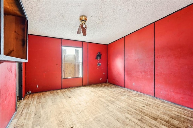 empty room with ceiling fan, light hardwood / wood-style floors, and a textured ceiling