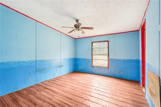 empty room with ceiling fan, light hardwood / wood-style flooring, ornamental molding, and a textured ceiling