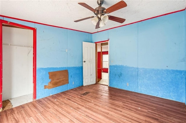 unfurnished bedroom with hardwood / wood-style floors, ceiling fan, crown molding, a textured ceiling, and a closet