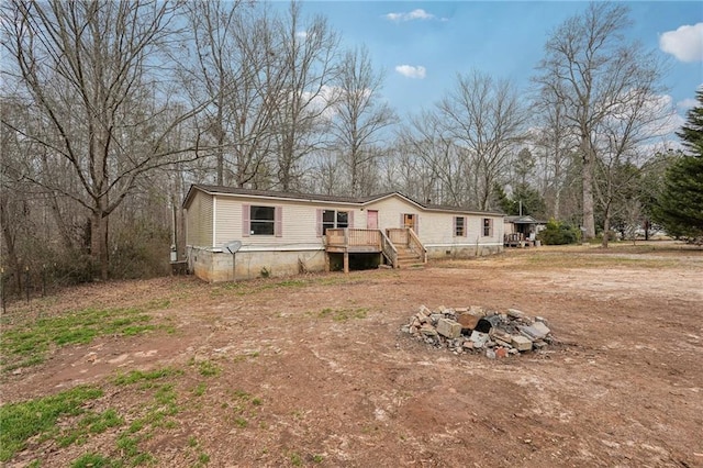 manufactured / mobile home featuring a wooden deck and an outdoor fire pit