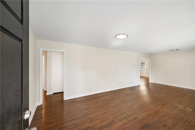 unfurnished room featuring dark wood-type flooring and baseboards