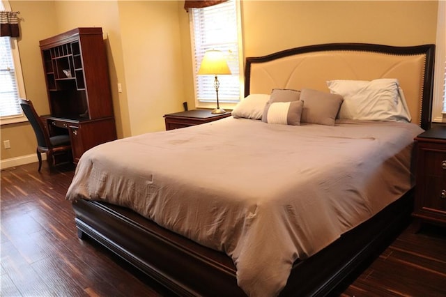 bedroom featuring multiple windows and dark wood-type flooring