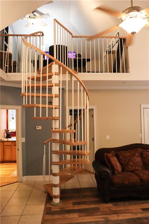 staircase featuring tile patterned floors, a towering ceiling, and ceiling fan