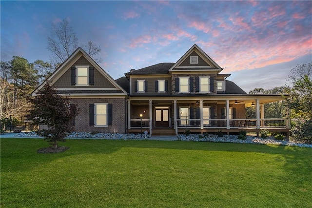 view of front of property featuring a porch, ceiling fan, and a lawn