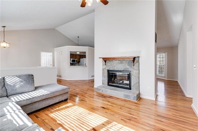 living room with a fireplace, wood finished floors, a ceiling fan, baseboards, and vaulted ceiling