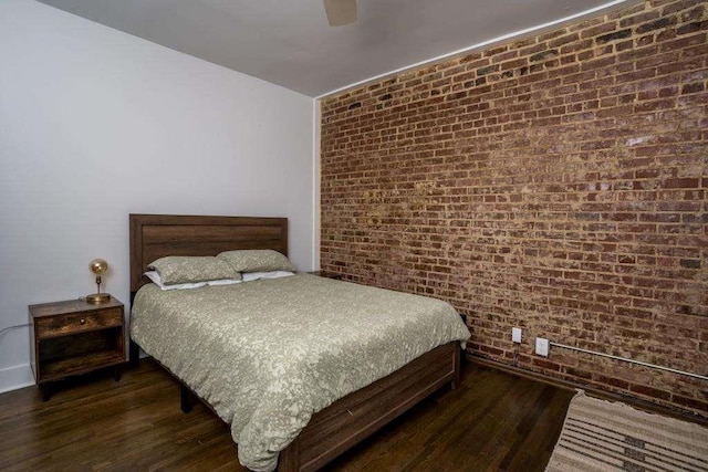 bedroom with ceiling fan, dark hardwood / wood-style floors, and brick wall