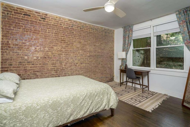 bedroom featuring hardwood / wood-style flooring, ceiling fan, and brick wall