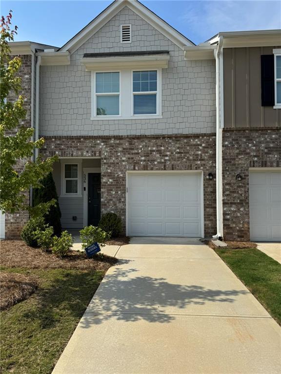 536 Magnolia Cir Unit 116, Palmetto, GA 30268 - view of property featuring a garage, concrete driveway, brick siding, and board and batten siding