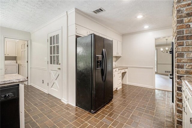 kitchen with black appliances, brick patterned flooring, a textured ceiling, washer / dryer, and white cabinetry