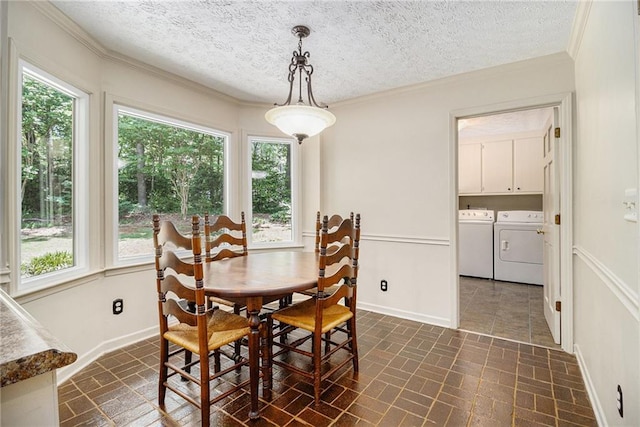dining space featuring brick patterned floors, independent washer and dryer, healthy amount of natural light, crown molding, and baseboards