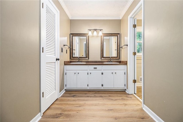 full bathroom with crown molding, double vanity, baseboards, and wood finished floors