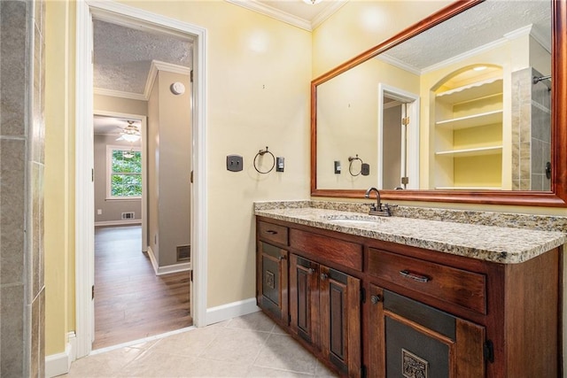 bathroom featuring a textured ceiling, built in features, baseboards, crown molding, and vanity