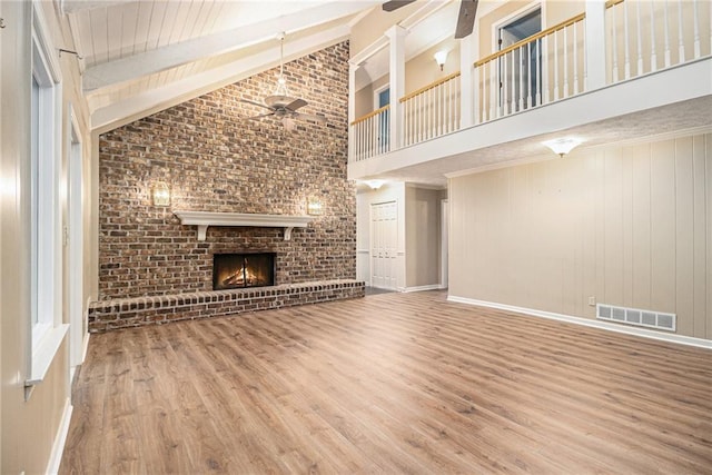 unfurnished living room with a ceiling fan, high vaulted ceiling, wood finished floors, a fireplace, and baseboards
