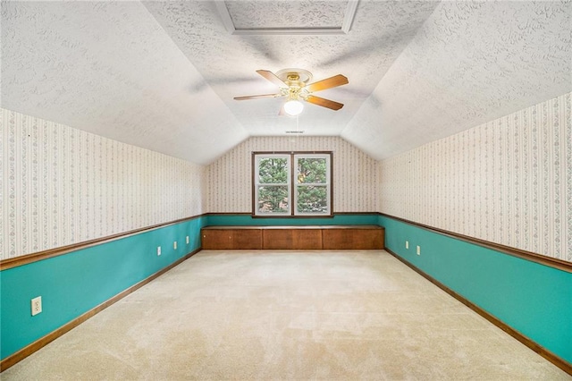 bonus room featuring a textured ceiling, wallpapered walls, vaulted ceiling, carpet, and baseboards