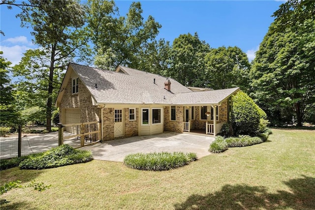 back of property with brick siding, a yard, roof with shingles, and a chimney