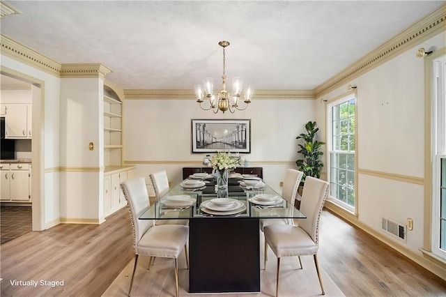dining area featuring light wood-style floors, a chandelier, baseboards, and crown molding