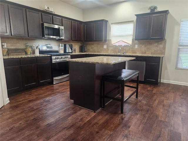 556 Emporia Loop, Mcdonough, GA 30253 - kitchen featuring stainless steel appliances, tasteful backsplash, dark wood-style floors, a center island, and light stone countertops
