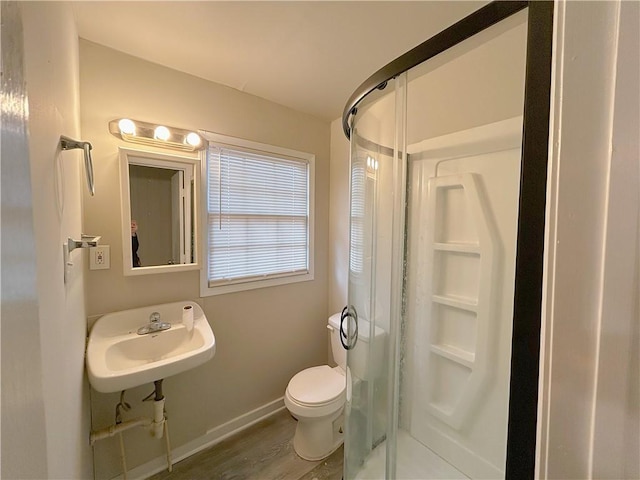 bathroom featuring a stall shower, baseboards, toilet, wood finished floors, and a sink