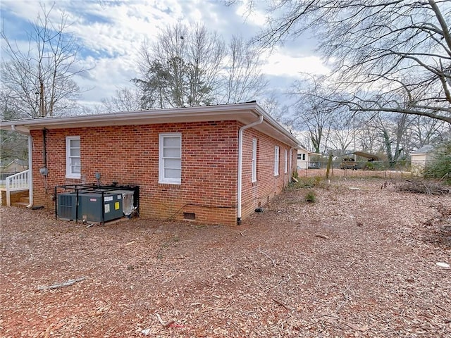 view of property exterior with brick siding, crawl space, and central AC unit