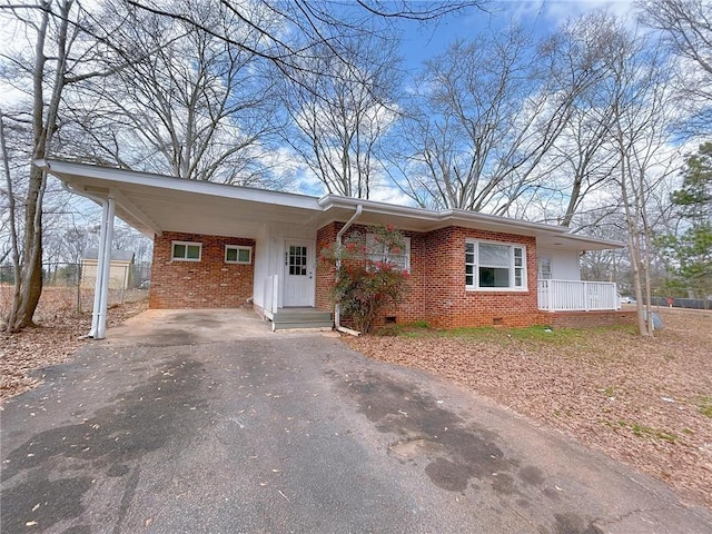 ranch-style house with crawl space, driveway, a carport, and brick siding